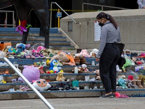 A woman pauses Thursday at the Calgary City Hall memorial to children who died at residential schools in Canada. Hundreds more unmarked graves have been discovered at a former residential school site in Saskatchewan.