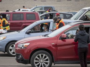 People sit in their vehicles while they wait to receive a COVID-19 vaccine at a drive-thru clinic at Richardson Stadium in Kingston, Ont., on Friday, May 28, 2021.