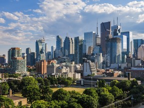 Downtown Toronto skyline: financial district skyscrapers with blue cloudy sky in the background and a park at the bottom