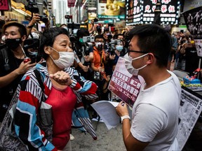 A pro-beijing protester, left, argues with Raphael Wong, right, from the League of Social Democrats at a street booth in the Causeway Bay district of Hong Kong on June 4, 2021, after police closed the venue where Hong Kong people traditionally gather annually to mourn the victims of China's Tiananmen Square crackdown in 1989 which the authorities have banned citing the coronavirus pandemic and vowed to stamp out any protests on the anniversary.