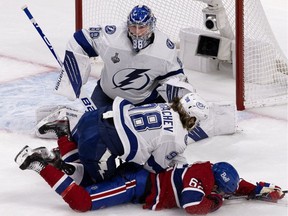 Tampa Bay Lightning defenceman Mikhail Sergachev knocks Montreal Canadiens left wing Artturi Lehkonen (62) to the ice and holds him out of harms way as Lightning goaltender Andrei Vasilevskiy (88) looks for the puck during game 3 of the Stanley Cup finals, in Montreal on Friday, July 2, 2021.