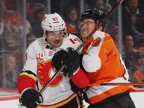 Robert Hagg (right) of the Philadelphia Flyers moves Michael Frolik of the Calgary Flames into the boards behind the net during the first period at the Wells Fargo Center on November 23, 2019 in Philadelphia, Pennsylvania.