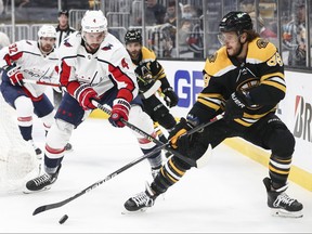 David Pastrnak (88) of the Boston Bruins vies for the puck with Brenden Dillon (4) of the Washington Capitals in Game Four of the First Round of the 2021 Stanley Cup Playoffs at TD Garden on May 21, 2021 in Boston.