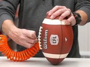 Stampeders Assistant Equipment Manager Gord Taillefer pumps up a football in the locker room in Calgary, June 14, 2021.