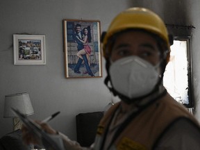 A fireman investigates the causes of the arson in the house of Italian citizen Giorgio Scanu (seen in the background picture) in the municipality of Santa Ana de Yusguare in Choluteca, Honduras, Friday, July 9, 2021.