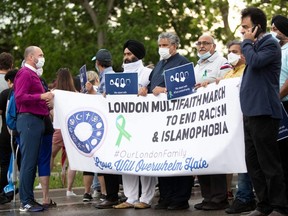 People hold a banner at the start of a multi-faith march to end hatred, on the site where a man driving a pickup truck struck and killed four members of a Muslim family in London, Ont., June 11, 2021.
