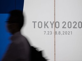 A man wearing a face mask walks past a display promoting the Tokyo 2020 on July 12, 2021 in Tokyo.
