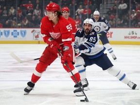 Tyler Bertuzzi of the Detroit Red Wings look to pass the puck in front of Mathieu Perreault of the Winnipeg Jets at Little Caesars Arena on December 12, 2019 in Detroit.
