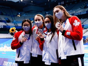 Silver medallists (from R) Canada's Penny Oleksiak, Canada's Kayla Sanchez, Canada's Rebecca Smith and Canada's Margaret Macneil pose on the podium after the final of the women's 4x100m freestyle relay swimming event during the Tokyo 2020 Olympic Games at the Tokyo Aquatics Centre in Tokyo on July 25, 2021. (Photo by Odd ANDERSEN / AFP)