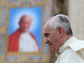 Pope Francis passes next to a tapestry of the late Pope John Paul II, as he leaves at the end of his weekly general audience at St. Peter's Square at the Vatican April 30, 2014.