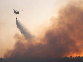 A chinook helicopter makes a water drop as a wildfire continues to rage in Varympompi, north of Athens, Greece, Wednesday, Aug. 4, 2021.
