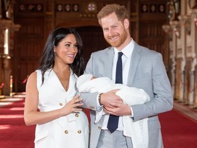 Prince Harry, Duke of Sussex (R), and his wife Meghan, Duchess of Sussex, pose for a photo with their newborn baby son, Archie Harrison Mountbatten-Windsor, in St George's Hall at Windsor Castle on May 8, 2019.