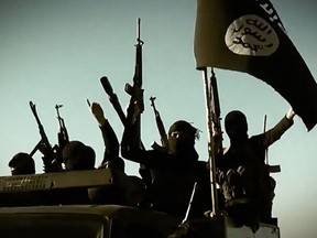 In this file image grab taken from a propaganda video released on March 17, 2014 by the Islamic State of Iraq and the Levant (ISIL)'s al-Furqan Media allegedly shows ISIL fighters raising their weapons as they stand on a vehicle mounted with the trademark Jihadists flag at an undisclosed location in the Anbar province.