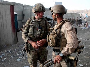 A handout picture released by the British Ministry of Defence shows a British soldier (left) and a member of the U.S. Armed Forces in conversation while working at Kabul Airport, on Sunday, Aug. 22, 2021.