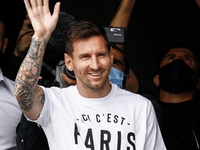 Argentine soccer player Lionel Messi salutes supporters from a window after he landed on Aug. 10, 2021 at Le Bourget airport, north of Paris.