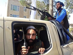 In this picture taken on August 13, 2021, Taliban fighters are pictured in a vehicle along the roadside in Herat, Afghanistan's third biggest city, after government forces pulled out the day before following weeks of being under siege.