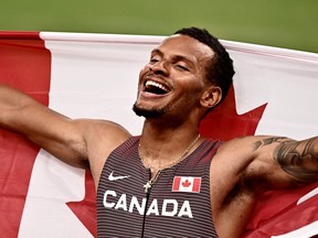 Andre De Grasse celebrates with the Canadian flag after winning gold after the men's 200m final during the Tokyo 2020 Olympic Games at the Olympic Stadium in Tokyo, Wednesday, Aug. 4, 2021.