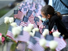 A family member at the reflecting pool places a flag  during a ceremony at the National September 11 Memorial & Museum commemorating the 20th anniversary of the September 11th terrorist attacks on the World Trade Center on Sept. 11, 2021 in New York City.
