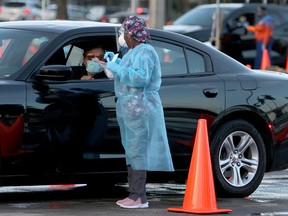 A health-care worker at a 24-hour drive-thru site set up by Miami-Dade and Nomi Health in Tropical Park prepares to administer a COVID-19 test on August 30, 2021 in Miami, Florida.