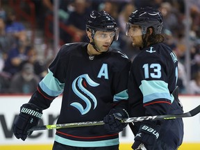 Mark Giordano #5 and Brandon Tanev #13 of the Seattle Kraken talk in the second period against the Vancouver Canucks during a preseason game at Spokane Veterans Memorial Arena on September 26, 2021 in Spokane, Washington.