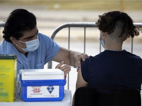 A health care worker administers a COVID-19 vaccination at a pop-up clinic at the Atwater Market in Montreal, on Sept. 2, 2021.