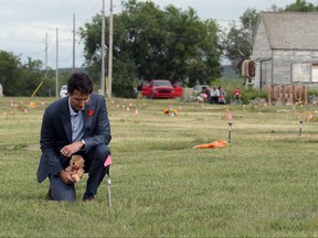 Canada's Prime Minister Justin Trudeau kneels to place a teddy bear at an unmarked grave on Cowessess First Nation, where a search had found 751 unmarked graves from the former Marieval Indian Residential School near Grayson, Sask., July 6, 2021.