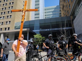 A protester carries a crucifix during an anti-vaccine mandate protest outside Toronto General Hospital in Toronto, Ontario, Canada September 13, 2021.  REUTERS/Chris Helgren