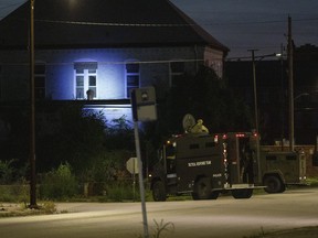 Illinois State Police in armoured trucks shine a spotlight on a building near St. Louis Avenue and Sixth Street in East St. Louis, Ill. during a manhunt after a shooting on Thursday, Sept. 9, 2021.
