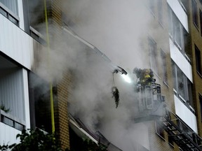 An emergency services crew works to evacuate people and put out fire as smoke comes out of windows after an explosion hit an apartment building in Annedal, central Gothenburg, Sweden Tuesday, Sept. 28, 2021.