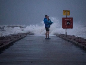 Local resident John Smith holds his 18-month-old son Owen as he stands near breaking waves on a pier ahead of the arrival of Tropical Storm Nicholas in Galveston, Texas, U.S., September 13, 2021.