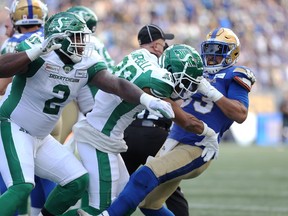 Winnipeg Blue Bombers RB Andrew Harris (right) throws Saskatchewan Roughriders DB Nick Marshall to the ground by the helmet during the Banjo Bowl in Winnipeg on Saturday, Sept. 11, 2021.