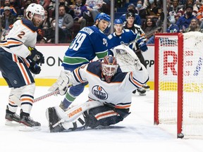 Edmonton Oilers goalie Mikko Koskinen watches the puck go wide of the net as Oilers' Duncan Keith (left) and Vancouver Canucks' Alex Chiasson look on during second period NHL hockey action in Vancouver, B.C., Saturday, Oct. 30, 2021.