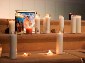 A photo of cinematographer Halyna Hutchins, who died after being shot by Alec Baldwin on the set of his movie "Rust", rests among candles at a vigil in Albuquerque, New Mexico, Oct. 23, 2021.