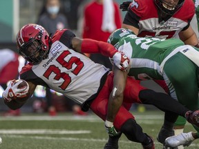 REGINA, SASK : October 9, 2021 -- Calgary Stampeders running back Ka'Deem Carey (35) is tackled by Saskatchewan Roughriders defensive back Godfrey Onyeka (26) at Mosaic Stadium on Saturday, October 9, 2021 in Regina. TROY FLEECE / Regina Leader-Post ORG XMIT: POS2110091944420115