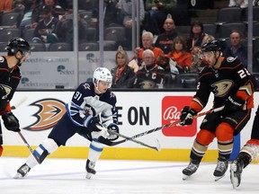 ANAHEIM, CALIFORNIA - OCTOBER 13: Cole Perfetti #91 of the Winnipeg Jets skates the puck against Kevin Shattenkirk #22 of the Anaheim Ducks in the first period at Honda Center on October 13, 2021 in Anaheim, California.