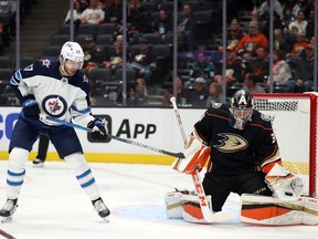 ANAHEIM, CALIFORNIA - OCTOBER 13: John Gibson #36 of the Anaheim Ducks makes a save in front of Adam Lowry #17 of the Winnipeg Jets in the first period at Honda Center on October 13, 2021 in Anaheim, California.