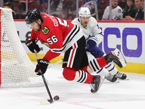 Erik Gustafsson #56 of the Chicago Blackhawks looses his balance trying to control the puck under pressure from Jason Spezza #19 of the Toronto Maple Leafs.