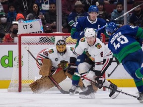 Chicago Blackhawks goalie Marc-Andre Fleury, back left, stops a shot from Vancouver Canucks' Quinn Hughes (43) as Chicago's Jake McCabe (6) defends and Vancouver's Bo Horvat (53) watches during first period NHL hockey action in Vancouver, B.C., Sunday, Nov. 21, 2021.