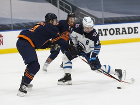 Edmonton Oilers defenceman Kris Russell (4) checks the Winnipeg Jets' Josh Morrissey (44) on March 18, 2021, in Edmonton.