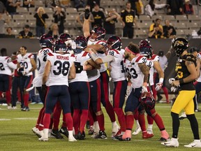 Alouettes players swarm kicker David Côté after his game-winning filed goal during overtime against the Tiger Cats in a game at Hamilton on Oct. 2.
