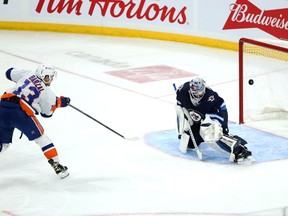 Winnipeg Jets goalie Eric Comrie (1) stops New York Islanders forward Mathew Barzal (13) during the third period at Canada Life Centre.