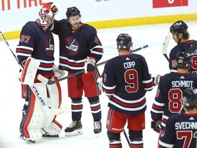 Winnipeg Jets goaltender Connor Hellebuyck (left) is congratulated by defenceman Neal Pionk after a win over the Edmonton Oilers in Winnipeg on Tues., Nov. 16, 2021. KEVIN KING/Winnipeg Sun/Postmedia Network