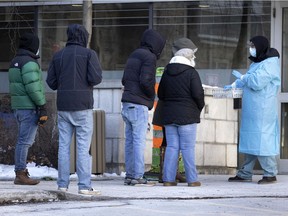 A health-care worker gives instructions to people lining up for a COVID-19 test at the Hôtel Dieu testing site in Montreal on Friday, Dec. 24, 2021.