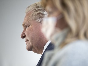 Ontario Premier Doug Ford stands alongside Health Minister Christine Elliott as he takes a question from the media following an announcement at Mississauga Hospital in Mississauga on December 1, 2021.