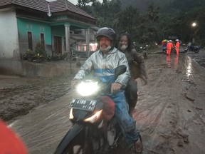 People ride a motorbike on a road that is covered with volcanic ash following an eruption of the Semeru mount volcano at Sumberwuluh village in Lumajang regency, East Java province, Indonesia, Dec. 4, 2021, in this photo taken by Antara Foto.