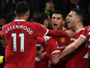 Manchester United's striker Cristiano Ronaldo (centre) celebrates with teammates after scoring the opening goal from the penalty spot during a Premier League match against Norwich City at Carrow Road Stadium in Norwich, England, Saturday, Dec. 11, 2021.