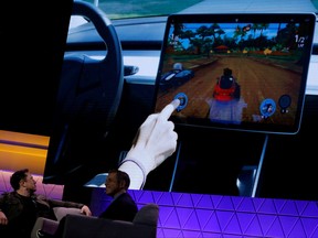 Tesla CEO Elon Musk, at the E3 gaming convention in Los Angeles, Calif., watches a clip of a videogame in a Model 3 vehicle on June 13, 2019.