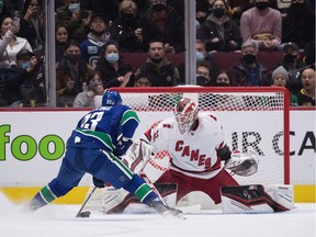 Carolina Hurricanes goalie Antti Raanta, right, stops Vancouver Canucks' Justin Dowling during first period NHL hockey action in Vancouver, B.C., Sunday, Dec. 12, 2021.