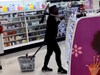 Woman holding pickaxe while pulling shopping basket in store.