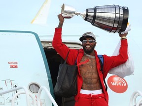 Defensive end Willie Jefferson carries the Grey Cup off the plane at Winnipeg International Airport as the Winnipeg Blue Bombers returned home as back-to-back CFL champions on Monday, Dec. 13, 2021.